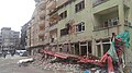2016 Hakkâri çatışmalarında hasar alan bir bina ve önündeki uzun araç