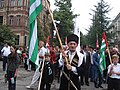 Zafer kutlamalarında kültürel kıyafetler içinde bayrak tutan Abhaz